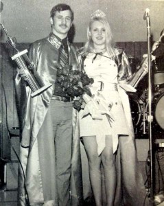 A young man and woman posing on a stage, holding trophies