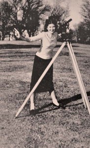 a woman poses with a piece of surveying equipment